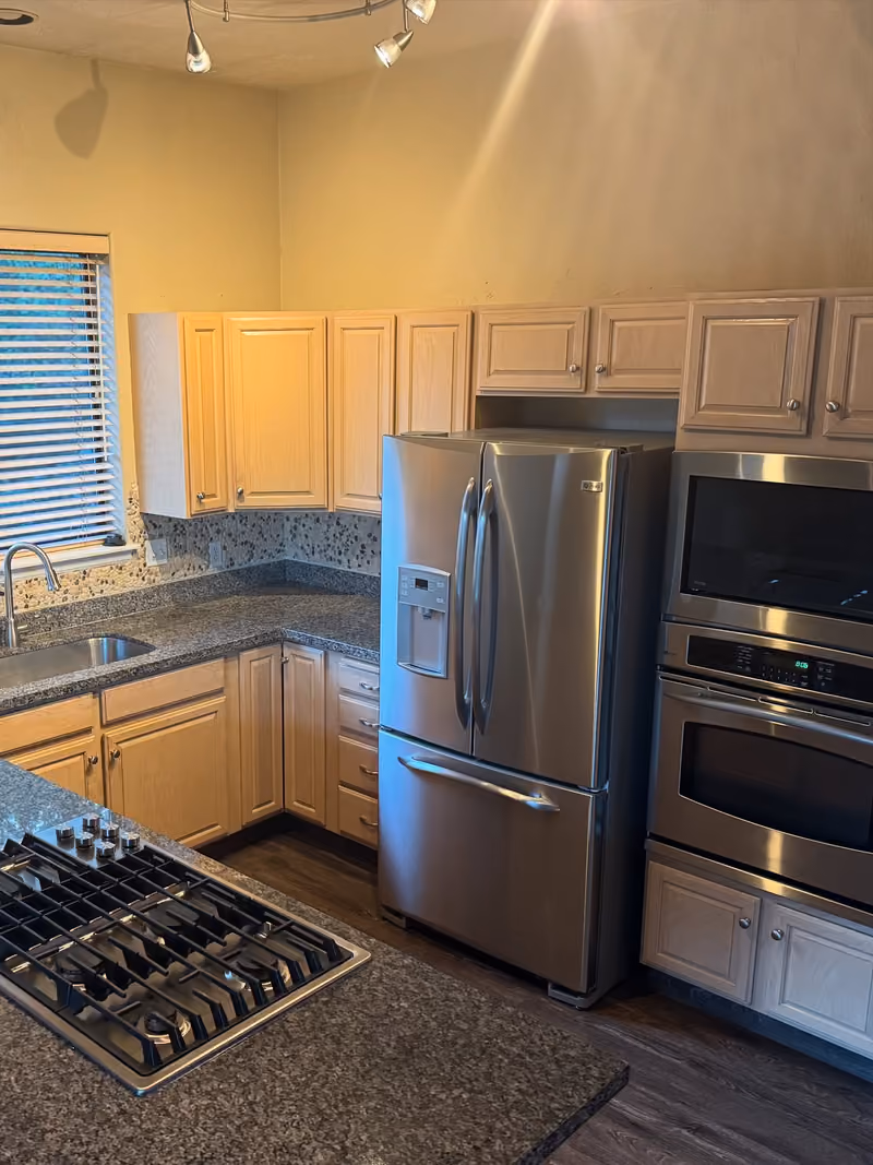 After: the same kitchen with clear granite counters and shining steel appliances